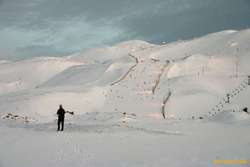 Bjöggi walking across snow covered Strompahraun, Bláfjall behind
